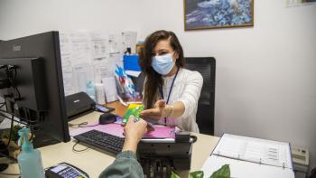 Patient remettant sa carte Vitale à un  personnel administratif assis à son bureau