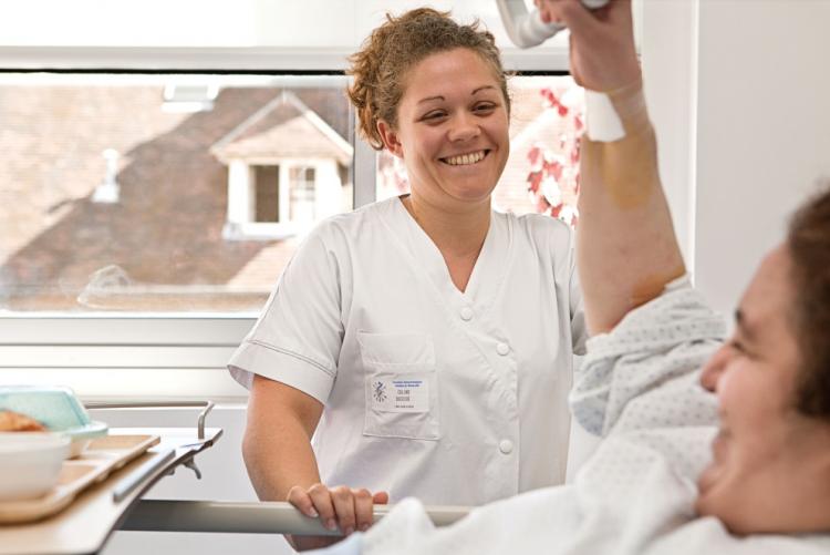 Une infirmière et un patient se regardent et sourient