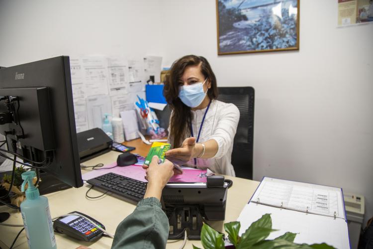 Patient remettant sa carte Vitale à un  personnel administratif assis à son bureau